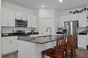 Kitchen with stainless steel appliances, dark countertops and a kitchen bar.