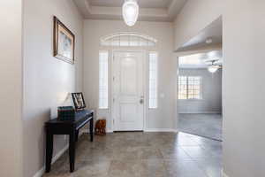 Foyer featuring baseboards, a raised ceiling, ceiling fan, and tile patterned floors
