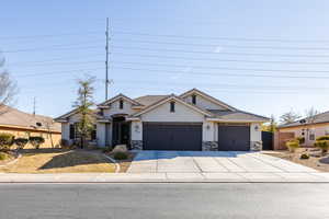 View of front of home featuring concrete driveway, stone siding, a garage, and stucco siding. 3rd car garage.