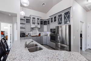 Kitchen with a sink, decorative backsplash, gray cabinets, visible vents, and appliances with stainless steel finishes