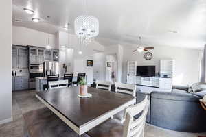 Dining area featuring visible vents, ceiling fan with notable chandelier, and high vaulted ceiling