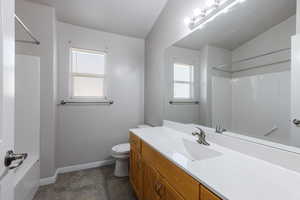 Full bathroom with baseboards, washtub / shower combination, toilet, and vanity