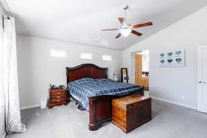 Primary bedroom featuring a ceiling fan, visible vents, vaulted ceiling, and baseboards.