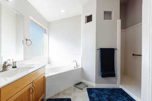 Primary bathroom with tile patterned floors, vanity, and a bath