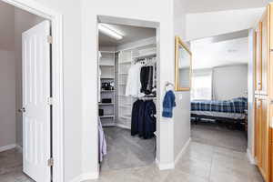 Walk in closet with light tile patterned floors, visible vents, and light colored carpet