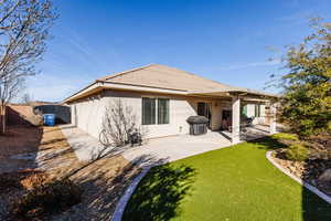 Back of house with a fenced backyard, stucco siding, a tile roof, a patio area, and AstroTurf lawn.