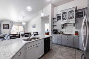 Kitchen featuring lofted ceiling, tasteful backsplash, a sink, gray cabinetry, and black dishwasher