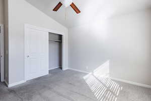 Unfurnished bedroom featuring carpet, vaulted ceiling, and a closet