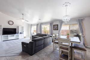 Living area with a healthy amount of sunlight, visible vents, vaulted ceiling, and ceiling fan with notable chandelier