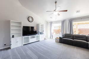 Living room with visible vents, ceiling fan, carpet flooring, and vaulted ceiling