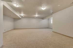 Basement featuring carpet, a textured ceiling, and baseboards
