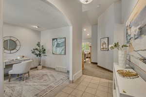 Office space featuring arched walkways, baseboards, light carpet, recessed lighting, and light tile patterned floors