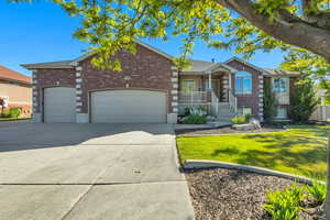 View of front of home featuring brick siding, an attached garage, driveway, and a front lawn