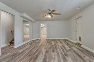 Unfurnished room featuring ceiling fan, wood finished floors, a textured ceiling, stairs, and baseboards