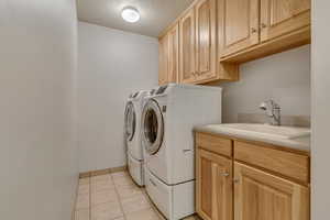 Washroom with washer and dryer, cabinet space, light tile patterned floors, and a textured ceiling