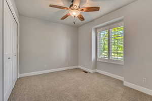 Unfurnished bedroom featuring a closet, baseboards, carpet, and ceiling fan