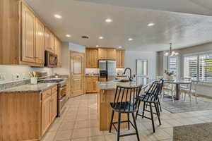 Kitchen featuring appliances with stainless steel finishes, a sink, a textured ceiling, recessed lighting, and a breakfast bar area