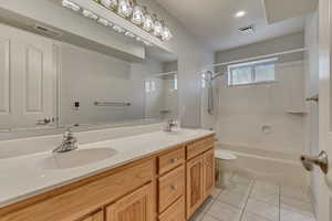 Bathroom with toilet, tile patterned flooring, shower / washtub combination, and double vanity