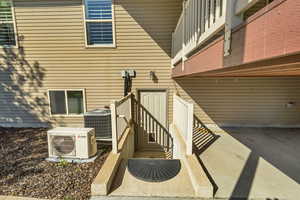 View of exterior entry with central AC and a cooling unit