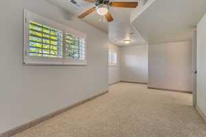 Carpeted spare room featuring ceiling fan and baseboards