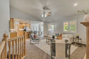 Living area featuring a ceiling fan, vaulted ceiling, light colored carpet, baseboards, and recessed lighting