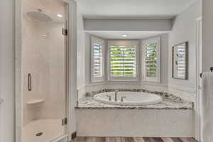 Bathroom featuring a marble finish shower, a bath, and wood finished floors