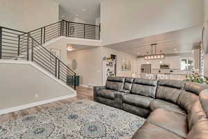 Living area with light wood-style flooring, stairway, a towering ceiling, baseboards, and recessed lighting