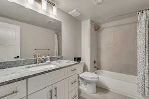 Bathroom with shower / bath combination with curtain, toilet, vanity, tile patterned floors, and a textured ceiling