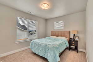 Carpeted bedroom featuring baseboards and a textured ceiling