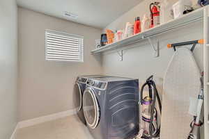 Laundry area featuring washing machine and clothes dryer, baseboards, and light tile patterned floors