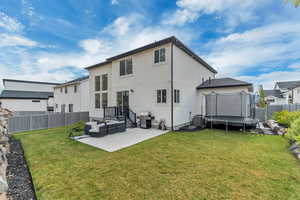 Back of house with a trampoline, a patio, outdoor lounge area, stucco siding, and central AC