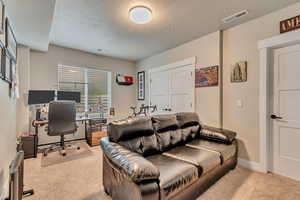 Carpeted office featuring a textured ceiling and baseboards
