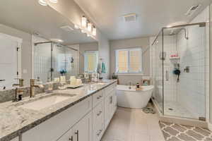 Bathroom with a stall shower, a soaking tub, double vanity, tile patterned floors, and a textured ceiling