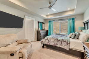 Carpeted bedroom with a raised ceiling, ceiling fan, a textured ceiling, and recessed lighting