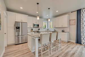 Kitchen featuring appliances with stainless steel finishes, light wood-style floors, decorative backsplash, a center island, and recessed lighting