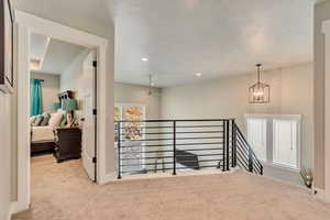 Hall featuring an upstairs landing, carpet floors, a chandelier, baseboards, and recessed lighting