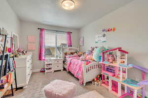 Bedroom featuring a textured ceiling, light colored carpet, and baseboards