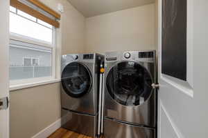 Laundry room with washing machine and clothes dryer, baseboards, and wood finished floors
