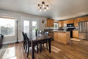 Dining room featuring wood finished floors, french doors, a chandelier, recessed lighting, and baseboards