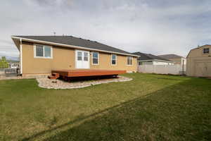 Back of house with a storage unit, an outdoor structure, and a deck
