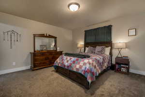 Carpeted bedroom featuring baseboards and a textured ceiling