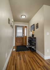 Doorway with wood finished floors, baseboards, and a textured ceiling