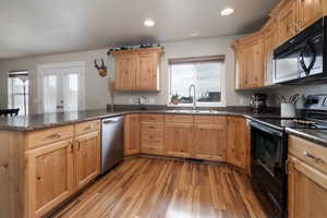 Kitchen featuring black appliances, a sink, a peninsula, healthy amount of natural light, and recessed lighting