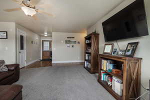Carpeted living room featuring baseboards, wood finished floors, and a ceiling fan