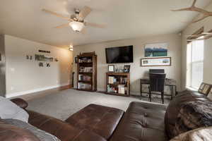 Carpeted living room with a ceiling fan and baseboards