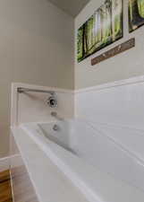 Full bath featuring a garden tub, baseboards, and wood finished floors