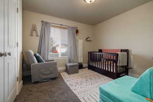 Bedroom with baseboards, carpet flooring, and a crib