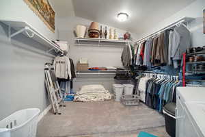 Upstairs Primary Suite Walk in closet featuring lofted ceiling, washer and dryer, and carpet