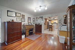 Office space with light wood-type flooring, rail lighting, crown molding, and a textured ceiling