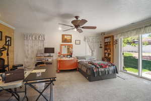 Main Floor Primary Bedroom featuring access to exterior, ornamental molding, light carpet, a textured ceiling, and a ceiling fan